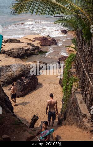 I turisti che discendono i gradini verso la spiaggia (Khola) (conosciuta anche come spiaggia segreta) e la laguna, Canacona, Goa, India Foto Stock