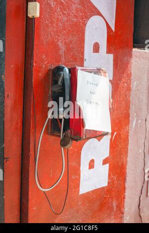 Telefono tradizionale rosso indiano a parete con mano scritta fuori ordine registrato sopra scatola, Margao, Goa, India Foto Stock