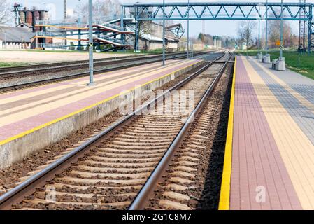 La ferrovia segue le riprese urbane. Linea leader view.Iron rusty treno dettaglio ferroviario su pietre scure ferrovia Foto Stock