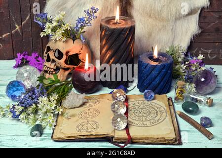 Ancora vita con libro aperto vacanze wiccan e simboli, fiori, cristallo e candele brucianti. Sfondo esoterico, gotico e occulto, mistico di Halloween Foto Stock