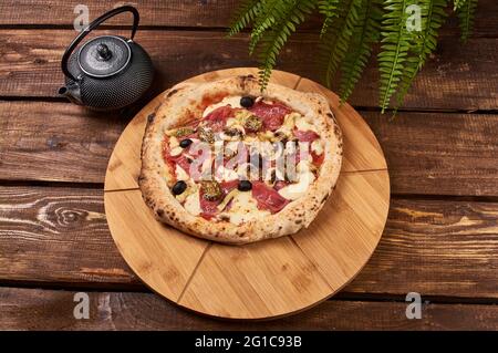 deliziosa pizza capriciosa su un supporto in legno Foto Stock