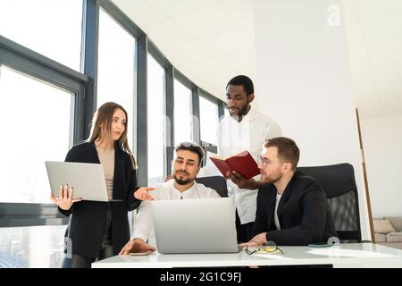 Gruppo di dipendenti di aziende multirazziali che lavorano su computer portatili Foto Stock