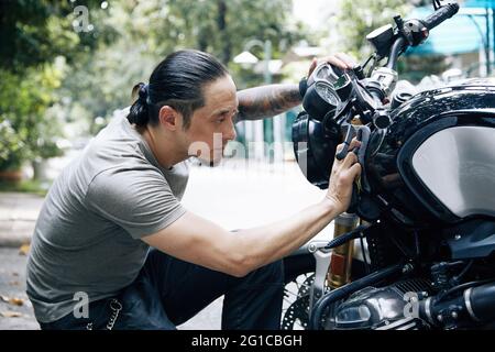 Bell'uomo che pulisce e strofina la sua moto con un panno morbido, dettagli moto o concetto di valeting Foto Stock