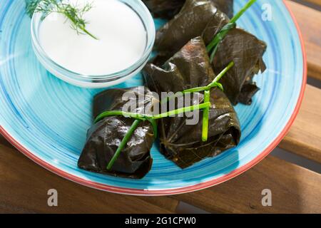 Involtini d'uva Sarni cotti in foglie e serviti con panna acida a piatto Foto Stock