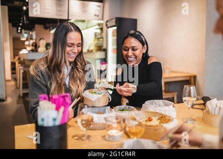 Felici le amiche che hanno cibo giapponese nel ristorante Foto Stock