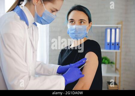 La donna bruna sta guardando il medico mentre viene vaccinata in ospedale Foto Stock