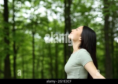 Vista laterale ritratto di una donna asiatica che respira aria fresca in una foresta Foto Stock