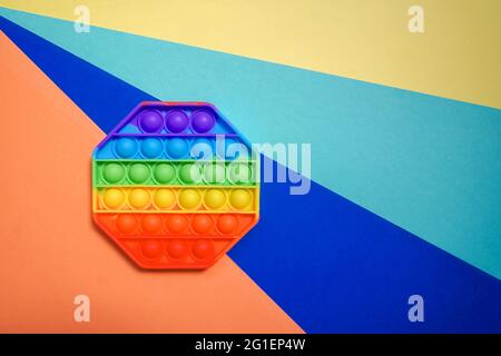Nuovo popolare giocattolo anti-stress colorato per bambini su sfondo colorato. Vista dall'alto, spazio di copia. Foto Stock