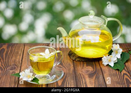tazza di vetro e teiera di tè verde con fiori di gelsomino Foto Stock
