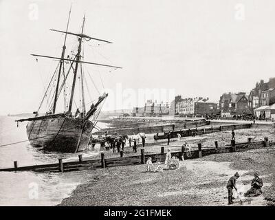 Una vista del tardo 19 ° secolo di una barca a vela spiaggiata sulle sabbie della Baia di Herne, una città di mare in Kent, Inghilterra. La città iniziò come una piccola comunità marittima, ricevendo merci e passeggeri da Londra durante il tragitto per Canterbury e dover. E 'salito alla preminenza come stazione balneare durante l'inizio del 19 ° secolo, dopo la costruzione di un molo di piacere e la passeggiata, quando i battelli a vapore ha iniziato a correre tra Herne Bay e Londra. Foto Stock