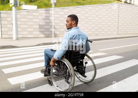 Giovane uomo nero disabile in sedia a rotelle che usa la passerella all'aperto. Concetto di qualità della vita e di compromissione Foto Stock