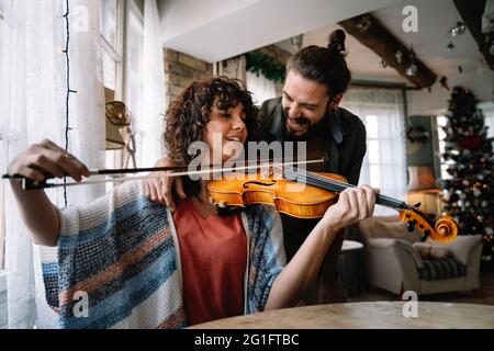 Insegnante privato di musica maschile che dà lezioni di violino a una donna a casa Foto Stock