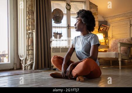 Stile di vita della salute e concetto di persone. Ritratto di giovane donna nera pacifica meditando all'interno Foto Stock