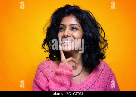 Bella Sri Lanka ragazza posa in piedi con giallo luminoso sfondo- La giovane donna sorride Foto Stock