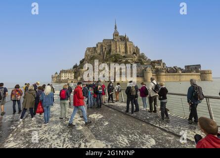 Francia, Manica (50), Baie du Mont-Saint-Michel, patrimonio mondiale dell'UNESCO, il Mont circondato dall'acqua dal ponte pedonale durante un'alta marea, i turisti guardare lo spettacolo e attendere la caduta della marea per passare Foto Stock