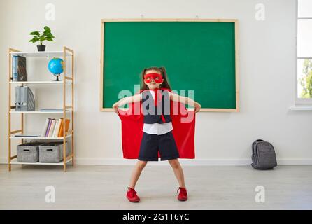 Ritorno a scuola. Supereroe divertente studentessa in piedi in classe. Foto Stock