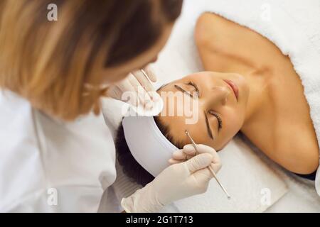 Cliente femminile che ottiene la pulizia profonda del viso fatta da cosmetica professionale usando gli attrezzi speciali Foto Stock