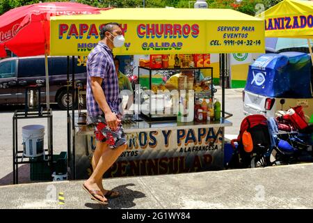 Covid-19 Pandemic: Uomo che indossa maschera a piedi in Merida Messico di fronte al carrello di cibo di strada Foto Stock