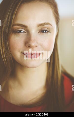 Foto di una donna europea intelligente e fiduciosa che sorride millennial in piedi con le braccia ripiegate a casa Foto Stock