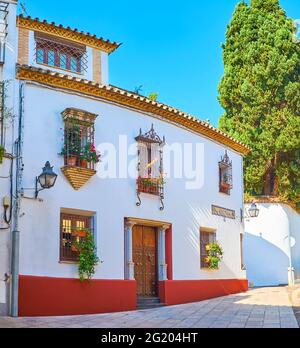 Il palazzo medievale in via Julio Romero de Torres, decorato con fiori in pentole, colonne di pietra, griglie ornamentali finestre, Cordoba, Spagna Foto Stock