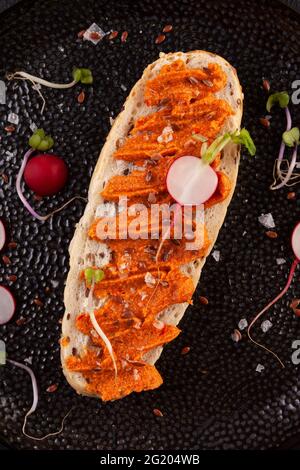 Baguette a grani interi con pepe spalmato. Ajvar - delizioso piatto di peperoni rossi, cipolle e aglio. Foto Stock