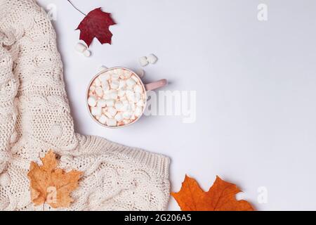 Composizione autunnale creativa con maglione a maglia calda, foglie di yllow e cacao con marshmallow Foto Stock