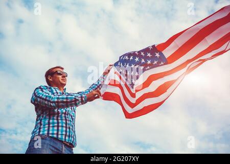 Uomo che tiene la bandiera degli Stati Uniti contro il cielo nuvoloso. Celebrazione della Giornata dell'Indipendenza dell'America. 4 luglio Foto Stock