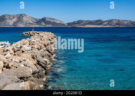 Vista del drone aereo di breakwater e beacon. Koufonisi isola porto marina parete rocciosa protezione, piccole Cicladi Grecia. Mare increspato e cielo blu chiaro Foto Stock