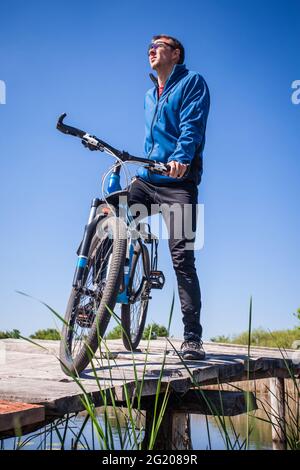 I giovani ciclisti si cavalcano in mountain bike sul ponte sul fiume Foto Stock