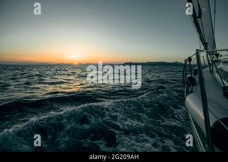 Tramonto dal ponte della barca a vela che si muove in un mare Egeo. Foto Stock