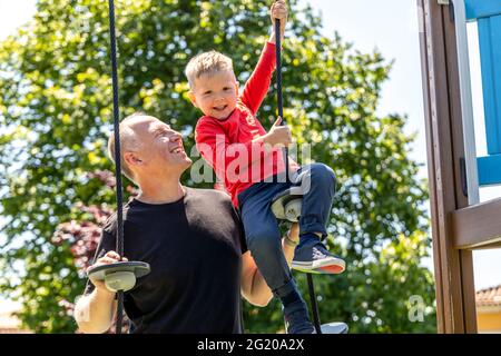 Padre che gioca con il suo figlio di 3 anni sul parco giochi Foto Stock