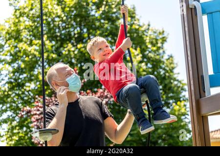 Padre che gioca con il suo figlio di 3 anni sul parco giochi Foto Stock