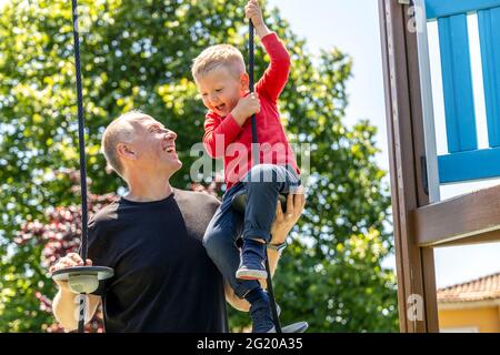 Padre che gioca con il suo figlio di 3 anni sul parco giochi Foto Stock