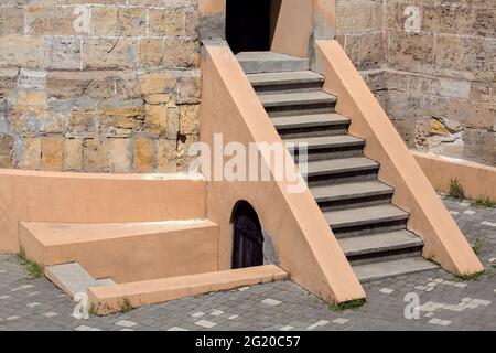 costruzione in pietra fortezza storica con scale su e giù per entrare la torre dal cortile con lastre di pavimentazione in una giornata di sole nessuno. Foto Stock