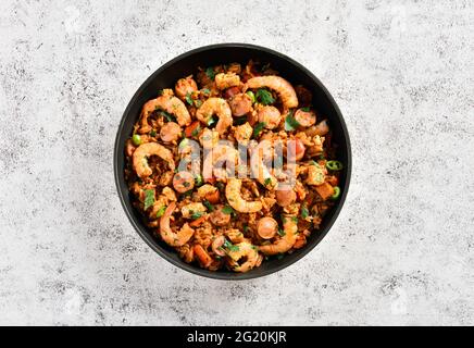 Creola jambalaya con pollo, salsicce affumicate e verdure su fondo di cemento. Vista dall'alto, disposizione piatta, primo piano Foto Stock