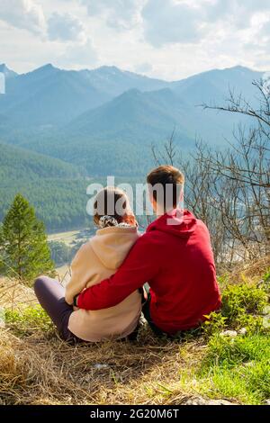 Giovane coppia di viaggiatori che riposa e prende selfie in montagna. Uomo e donna trekking con zaini su un bellissimo sentiero roccioso. Viaggi locali con la famiglia Foto Stock