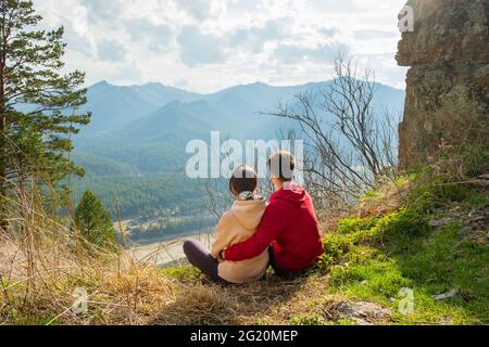 Giovane coppia di viaggiatori che riposa e prende selfie in montagna. Uomo e donna trekking con zaini su un bellissimo sentiero roccioso. Viaggi locali con la famiglia Foto Stock