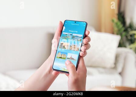 Scelta di una destinazione di viaggio con concetto di smartphone. App moderna con opzione Scegli un viaggio. Telefono in mano donna. Primo piano. Foto Stock