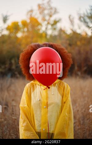 Ritratto di una ragazza sorridente vestita di impermeabile in posa. Donna cammina nel bosco in un impermeabile giallo, in attesa della pioggia. Foto Stock