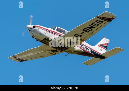 1978 Piper PA-28 aereo Cherokee Arrow III che vola in cielo azzurro sull'aeroporto di Southend, Essex, Regno Unito. Buona visibilità volo privato. Sporco Foto Stock