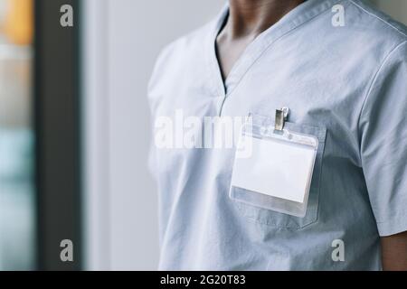 Primo piano di un medico non riconoscibile che indossa un ID vuoto su uno spazio uniforme per la copia Foto Stock