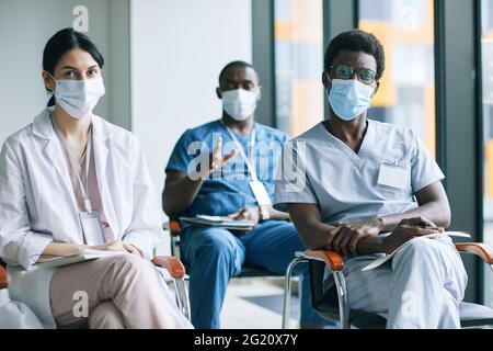 Diversi gruppi di medici che indossano maschere durante la conferenza medica o seminario Foto Stock