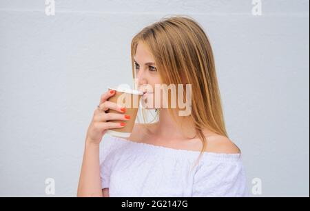 Bella donna che beve caffè takeaway. La ragazza beve espresso, latte, cappuccino in tazza di carta. Foto Stock