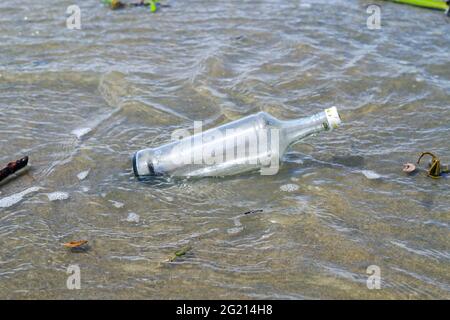 Inquinamento delle bottiglie d'acqua in vetro nell'oceano (concetto di ambiente). Inquinamento dell'oceano: Rifiuti sulla spiaggia. Foto Stock