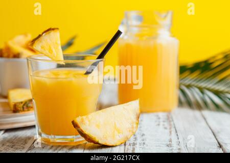 Saporito succo di ananas in vetro con ingredienti. Cocktail di succo di ananas fresco naturale e succo di ananas in caraffa di vetro su tavolo di legno bianco con Foto Stock