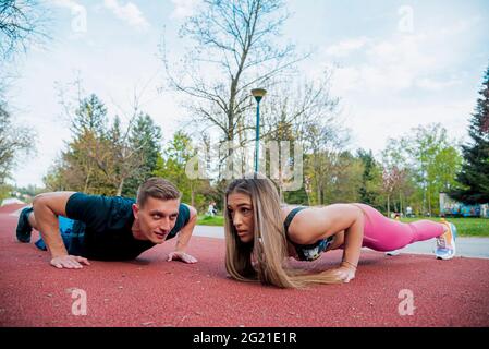 Colpo di giovane coppia sana facendo esercizi di stretching insieme sul prato verde al mattino Foto Stock