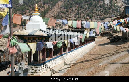 Preghiera buddista molti muri con ruote di preghiera e bandiere di preghiera nel villaggio nepalese, percorso di trekking circuito Annapurna, Nepal Foto Stock