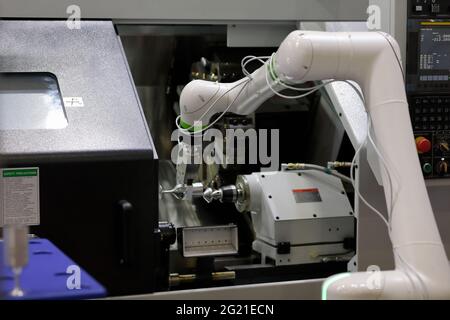 Tornio CNC e robot collaborativo che caricano il pezzo Foto Stock