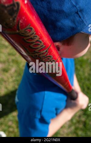 Bambino che tiene una mazza da baseball in un campo. Foto Stock