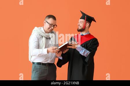 Felice studente di laurea maschile con suo padre su sfondo a colori Foto Stock